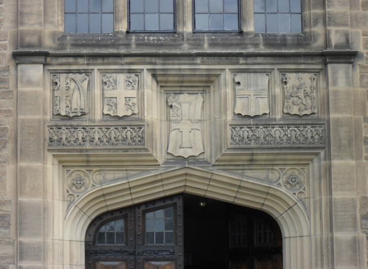 Detail of the facade showing (from left to right) the coats of arms of Van Mildert, the Prince Bishop who founded Durham University; the Bishopric of Durham, Durham University, the City of Durham. The coat of arms to the far right is yet to be identified.  