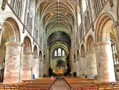 The nave of Hereford Cathedral showing the rounded arches of the Norman period above which are the pointed arches and elaborate rib vaulting of 14th century Gothic. 
